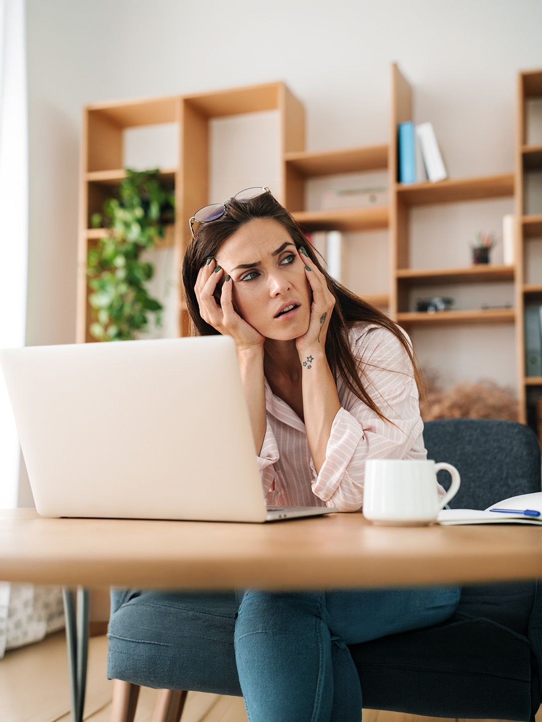 Frustrierte Unternehmerin sitzt mit dem Kopf in den Händen vor ihrem Laptop