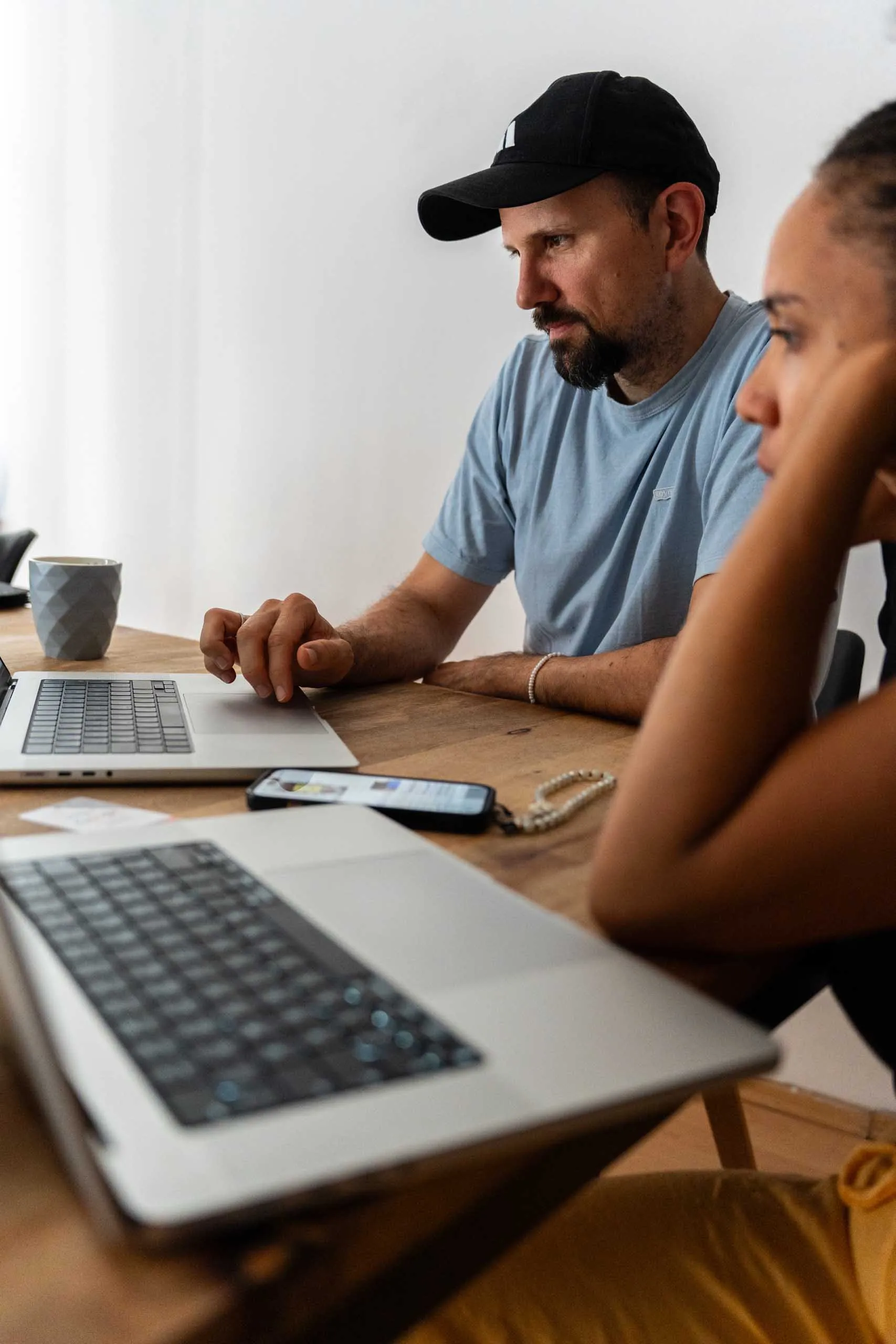 Zwei Teammitglieder arbeiten gemeinsam an Laptops am Besprechungstisch