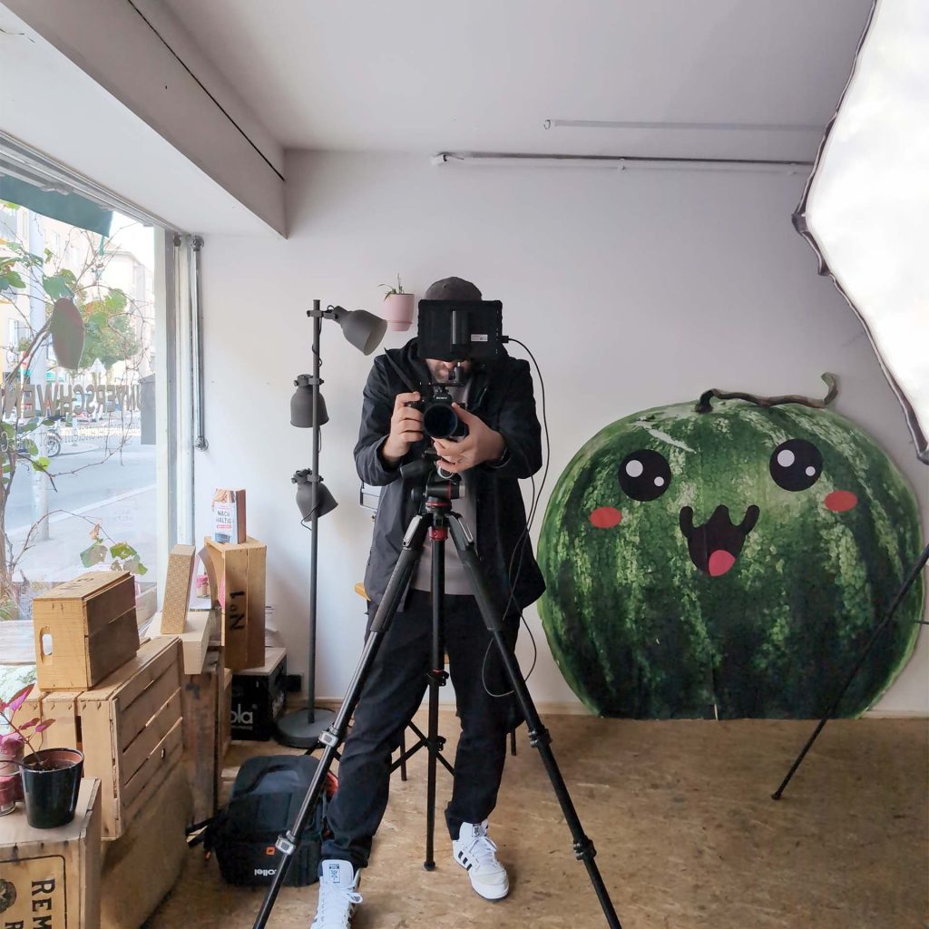 Unverschwendet Performance Marketing 3 Markus bei der Content-Produktion im Unverschwendet-Atelier mit Kamera und lächelnder Wassermelonen-Figur.