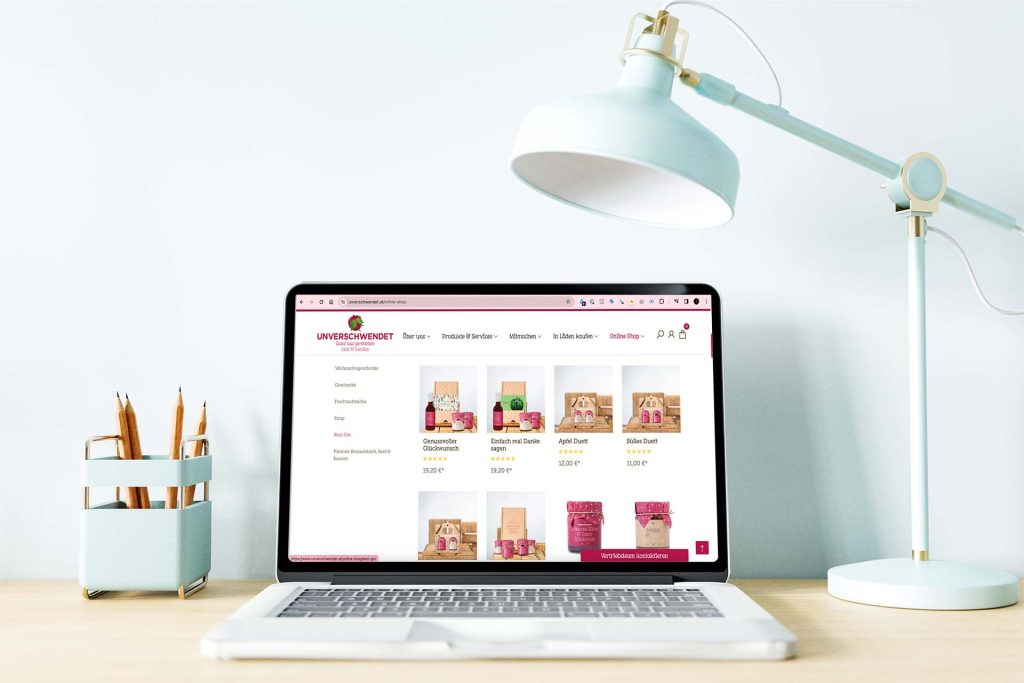 Der Unverschwendet-Onlineshop mit Geschenksets und Fruchtaufstrichen auf einem Laptop am Schreibtisch.