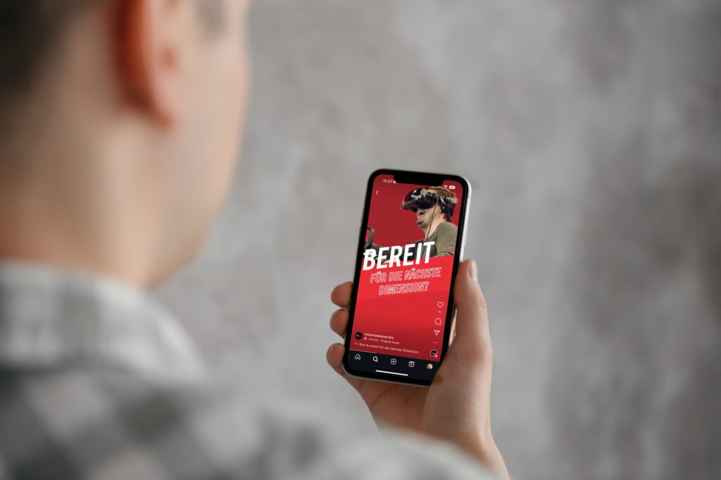 Person hält Smartphone mit Instagram-Reel der Rotax MAX Dome Kampagne, zeigt VR-Brille und Slogan „Bereit für die nächste Dimension?“