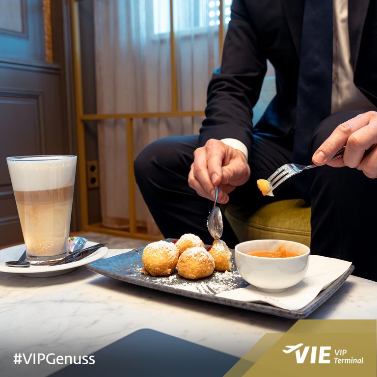 Social Media & Content Marketing für VIP Terminal Vienna Airport 7 Person im Anzug genießt Topfenknödel mit Marillenröster und Latte Macchiato im VIP Terminal, Szene voller Genussmoment.