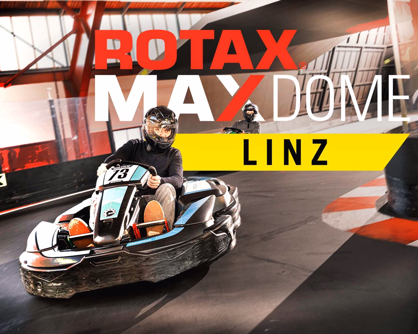 Fahrer im E-Kart auf Indoor-Strecke, darüber Schriftzug „ROTAX MAX DOME LINZ“ in rot, weiß und gelb vor Hallenkulisse.