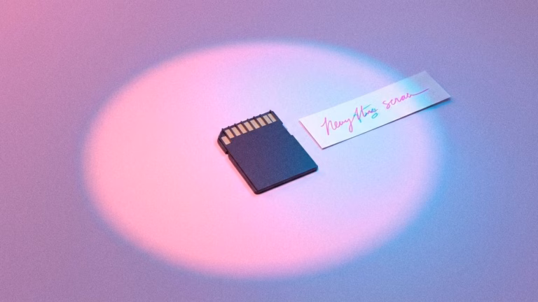 Ein SD-Speicherchip und ein Zettel mit Schrift darauf auf einer rosa-blauen Oberfläche.
