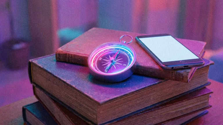 Kompass und Handy auf Büchern.
